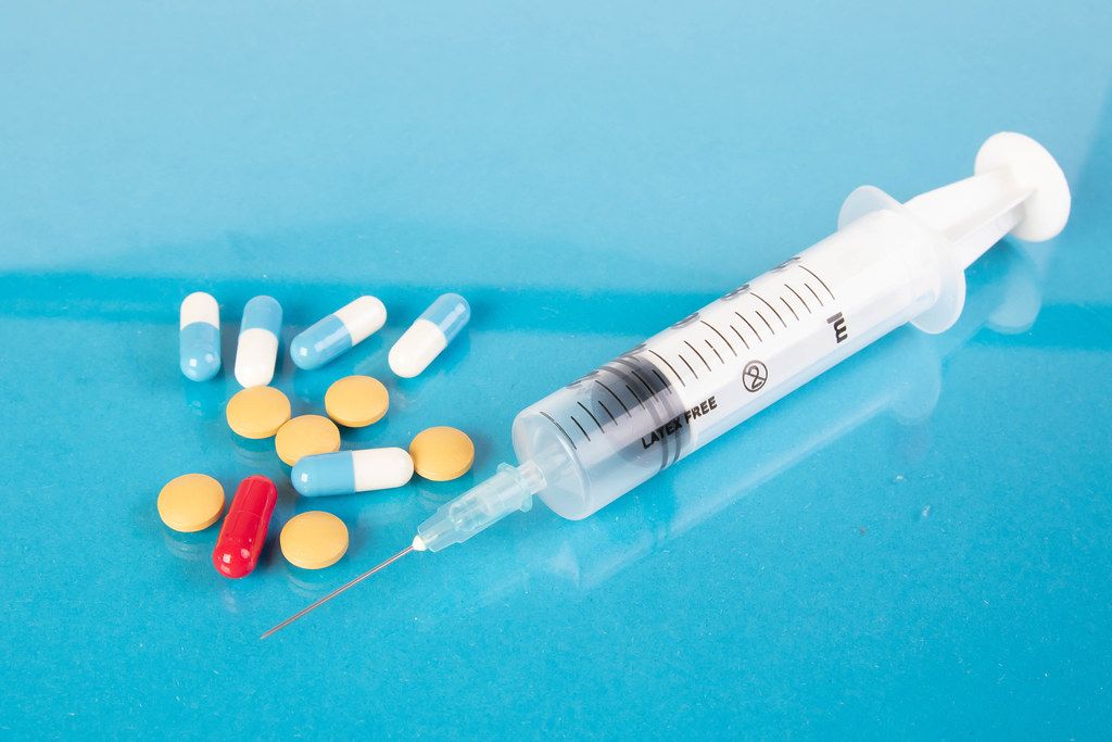 Medical syringe and pills on blue background