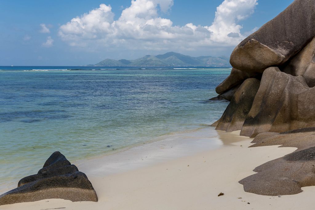 Mehrfarbig Steine aus Granit am Anse Source d'Argent-Strand von La Digue, neben dem Indischen Ozean und mit Blick auf Praslin