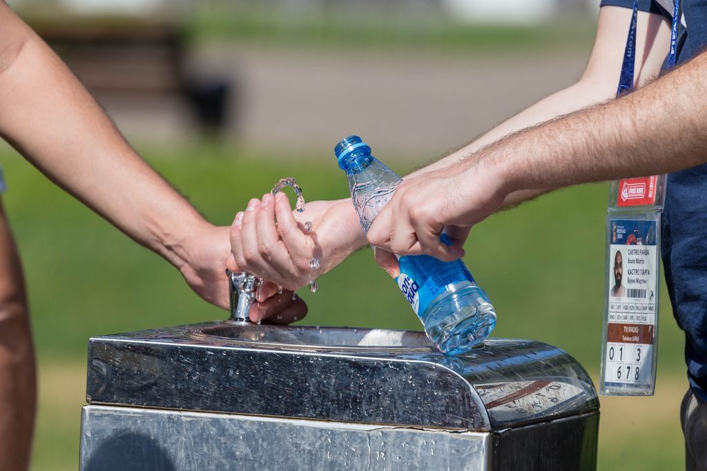 Men filling a plastic bottle with water at a drinking fountain