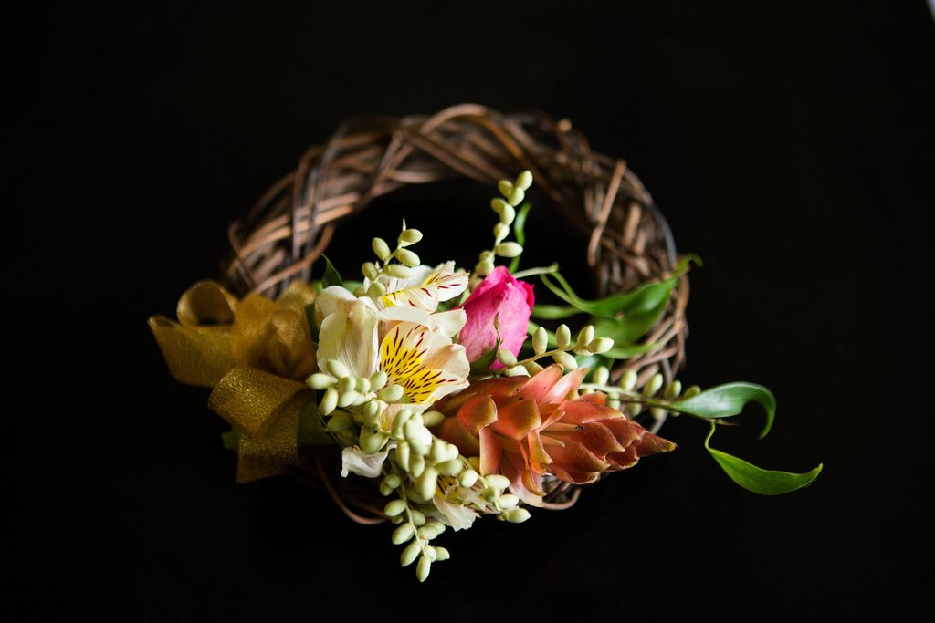 Mit Blumen und Blüten verzierter Kranz eines Blumenmädchens vor schwarzem Hintergrund
