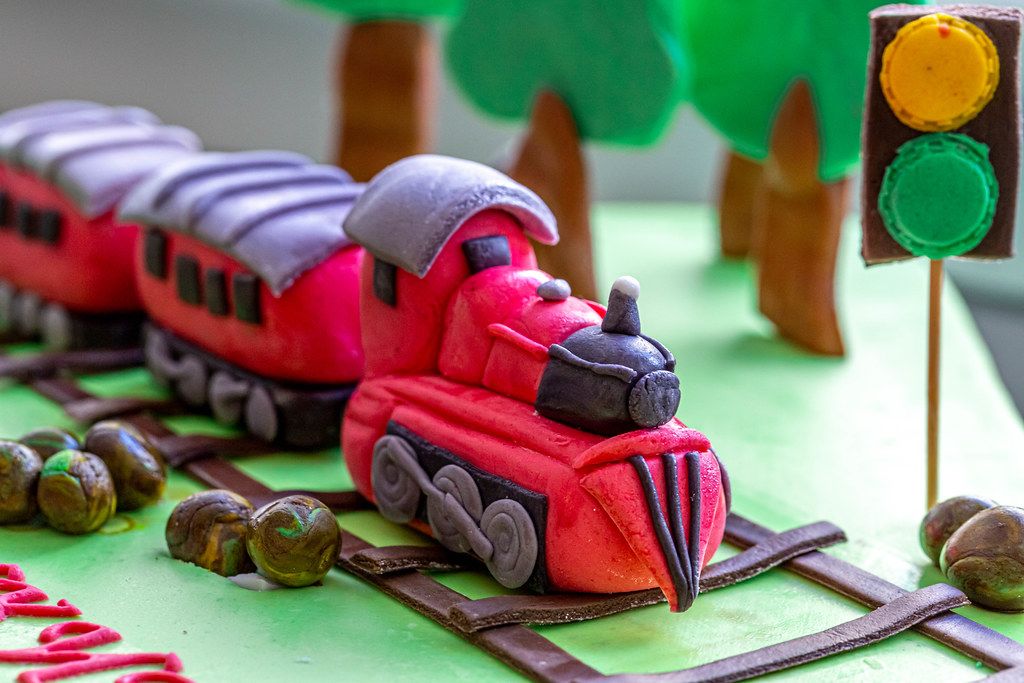 Nahaufnahme eines dekorierten Geburtstagskuchen für Kinder, mit roter Eisenbahn auf einer Zugstrecke