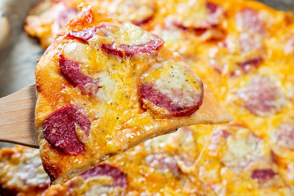 Nahaufnahme eines Stückes heißer Pizza mit Käse und Wurst - Creative