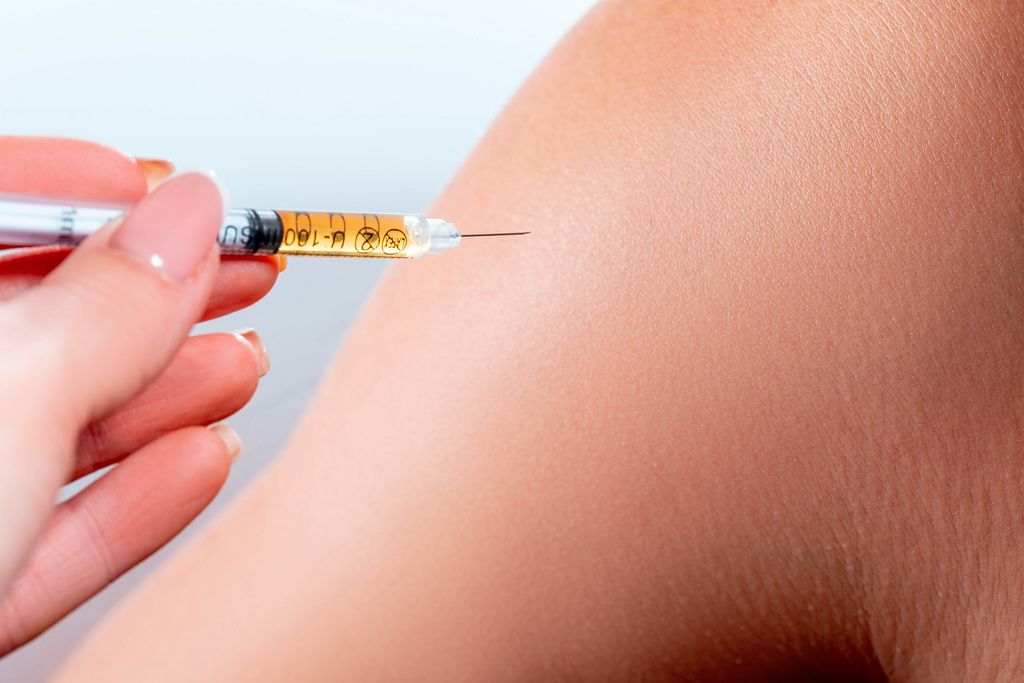 Nahaufnahme Frauenhand injiziert Insulin aus Spritze in Oberarm
