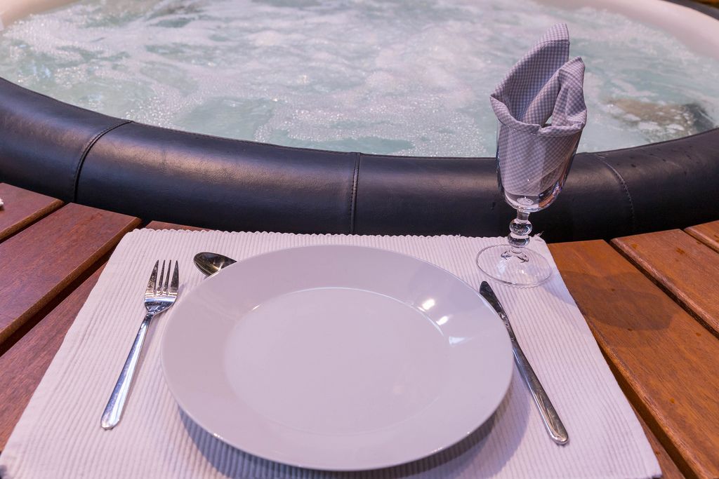 Nahaufnahme Tischgedeck mit Teller, Besteck und Glas auf Ablage vor Whirlpool