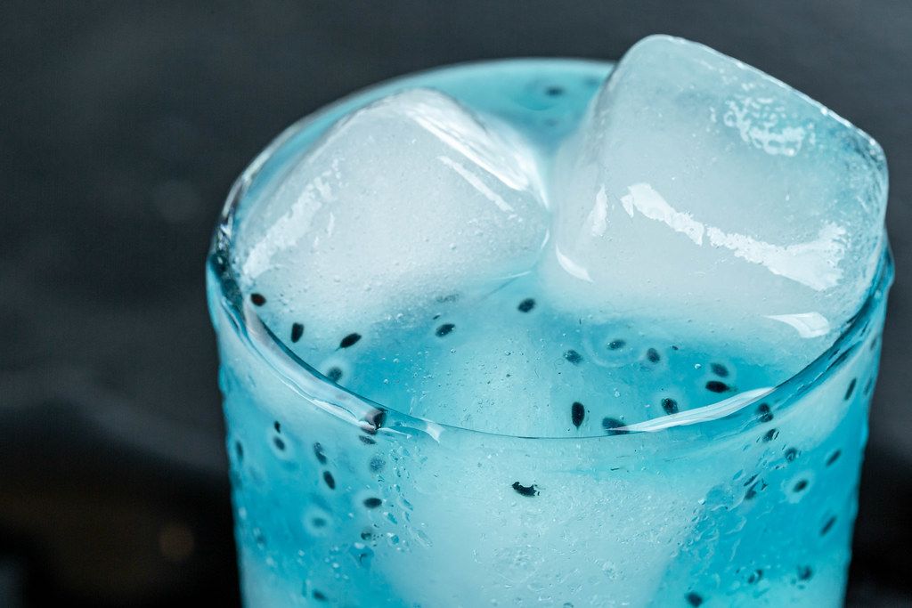 Nahaufnahme von einem blauen Cocktail im Glas, mit Eiswürfeln gefüllt