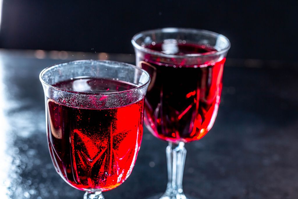 Nahaufnahme von zwei Weingläsern gefüllt mit Rotwein vor dunklem Hintergrund