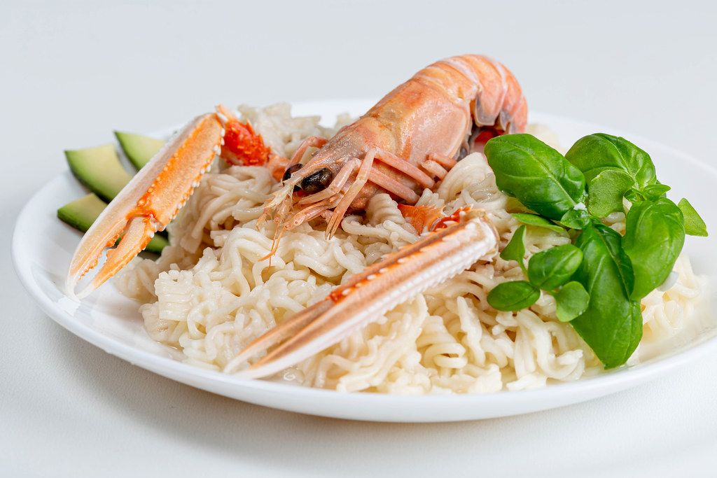 Noodles with fresh basil and lobster on a white background