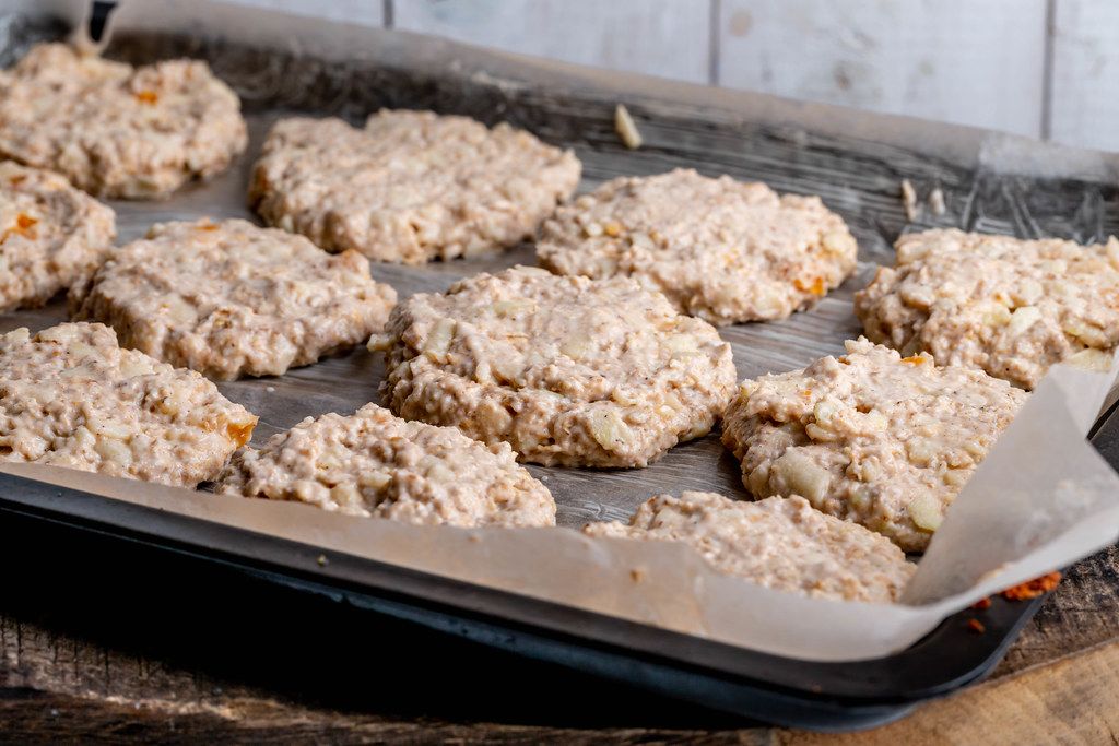 Oatmeal cookies dough with apples and dried apricots on a baking sheet before baking (Flip 2019)