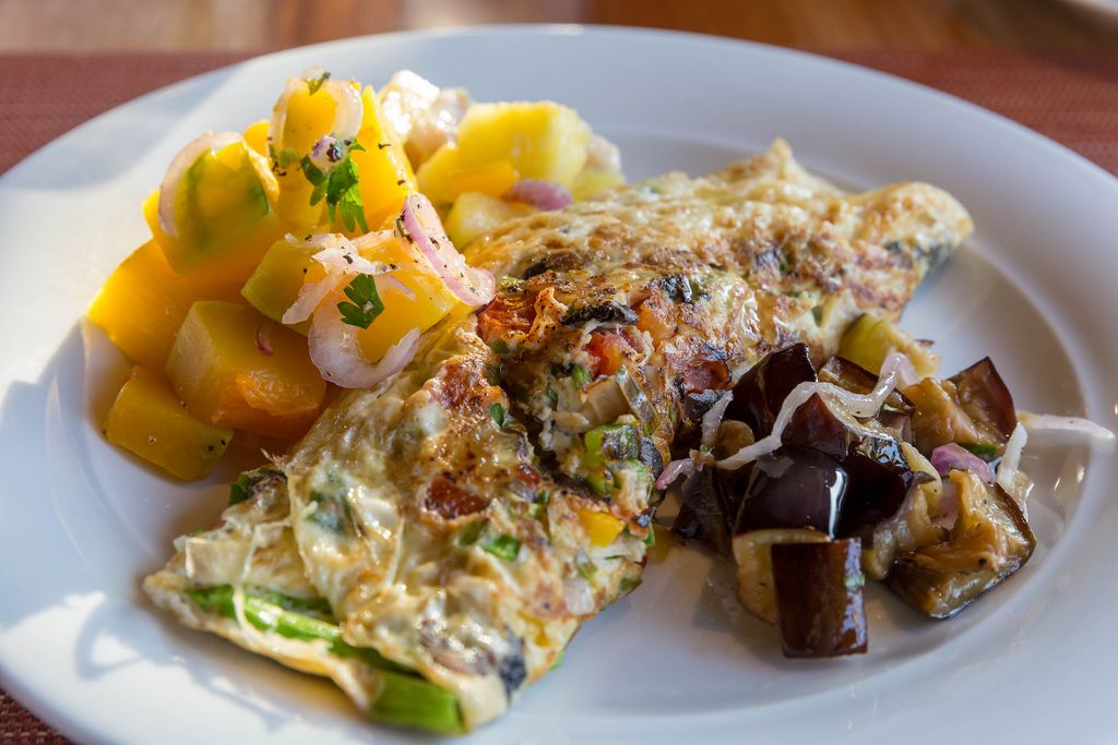 Omelette with Mango fruit salad and eggplants on white plate