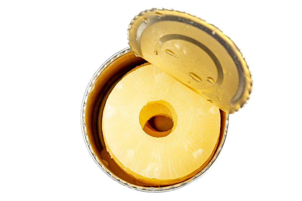 Open a tin of pineapples in syrup on white background