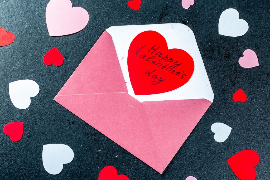 Open envelope with a red card-heart and wishes of happy Valentine's day