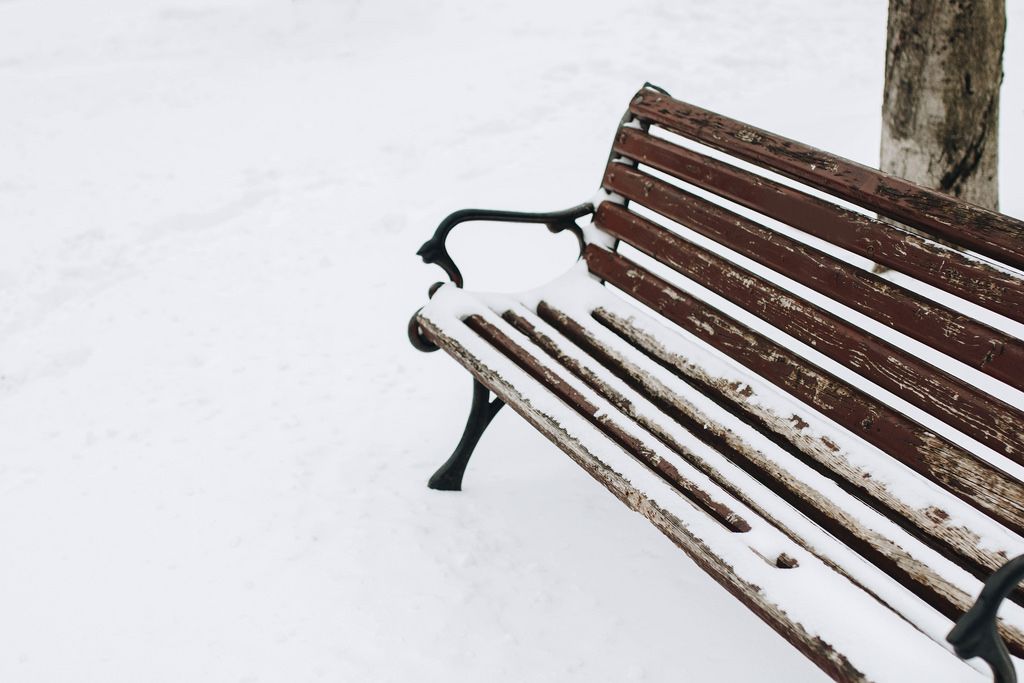 Outdoor shot of wooden bench covered with snow. Winter.