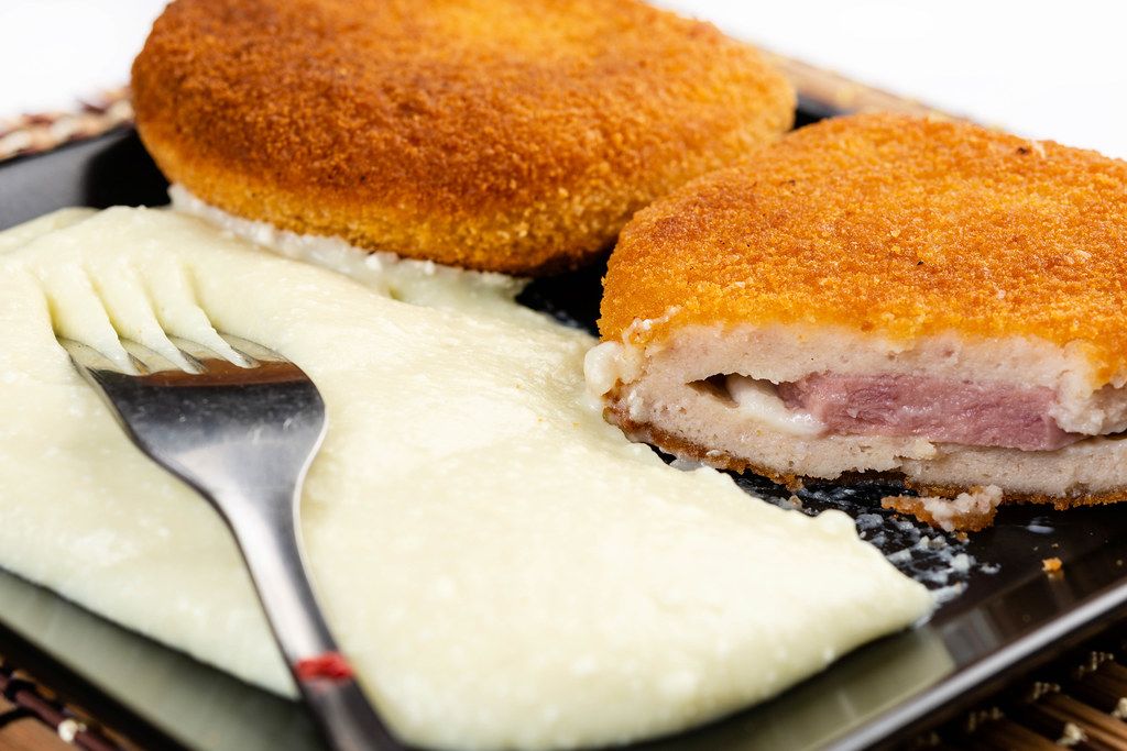 Paniertes Putenfleisch mit Käse-Schinken-Füllung à la Cordon bleu auf einem Teller