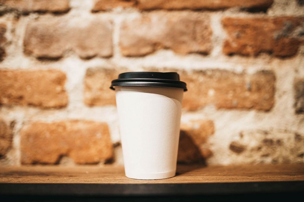 Paper coffee cup on brick wall background