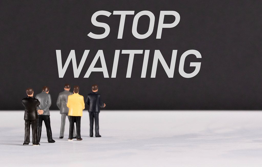 People standing in front of Stop Waiting text