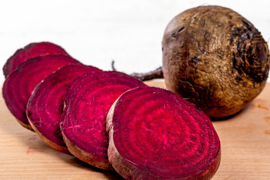 Pieces of chopped beet and whole beet on white background