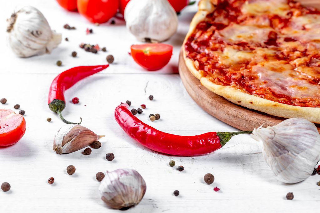 Pizza with garlic, pepper, chili and tomatoes on the table
