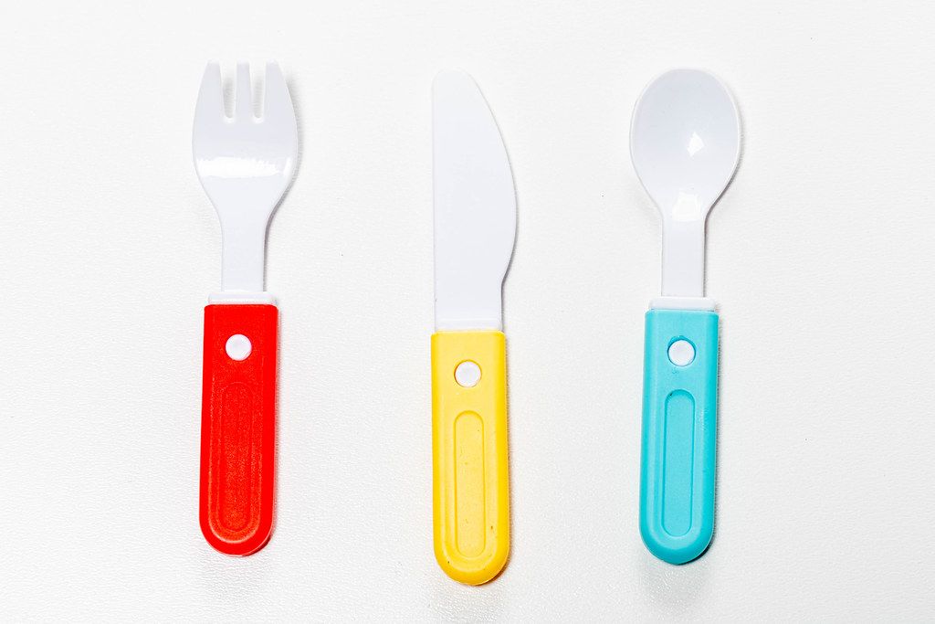 Plastic knife, fork and spoon on white background. Children's toy (Flip 2019)