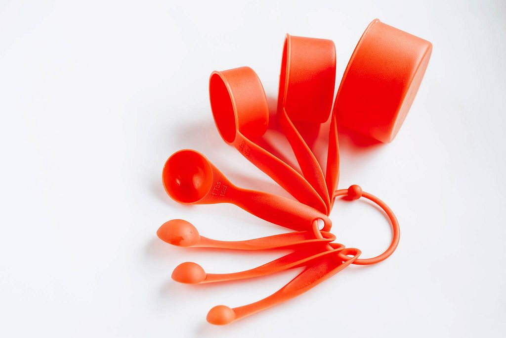 Plastic measuring cups and spoons on white background.