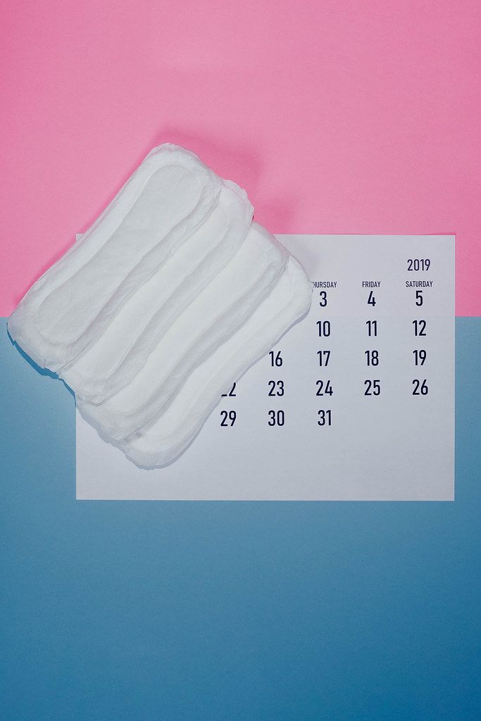 PMS, period days or menstrual cycling concept. Top view of the calendar and sanitary napkins
