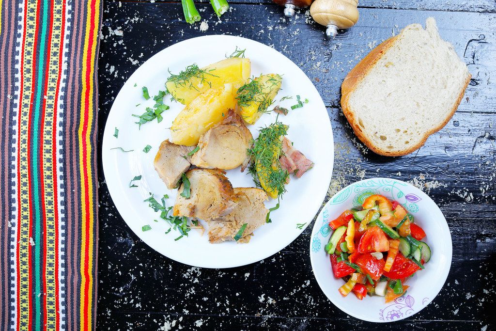 Pork roast with bread and mixed vegetable salad. Black background (Flip 2019)