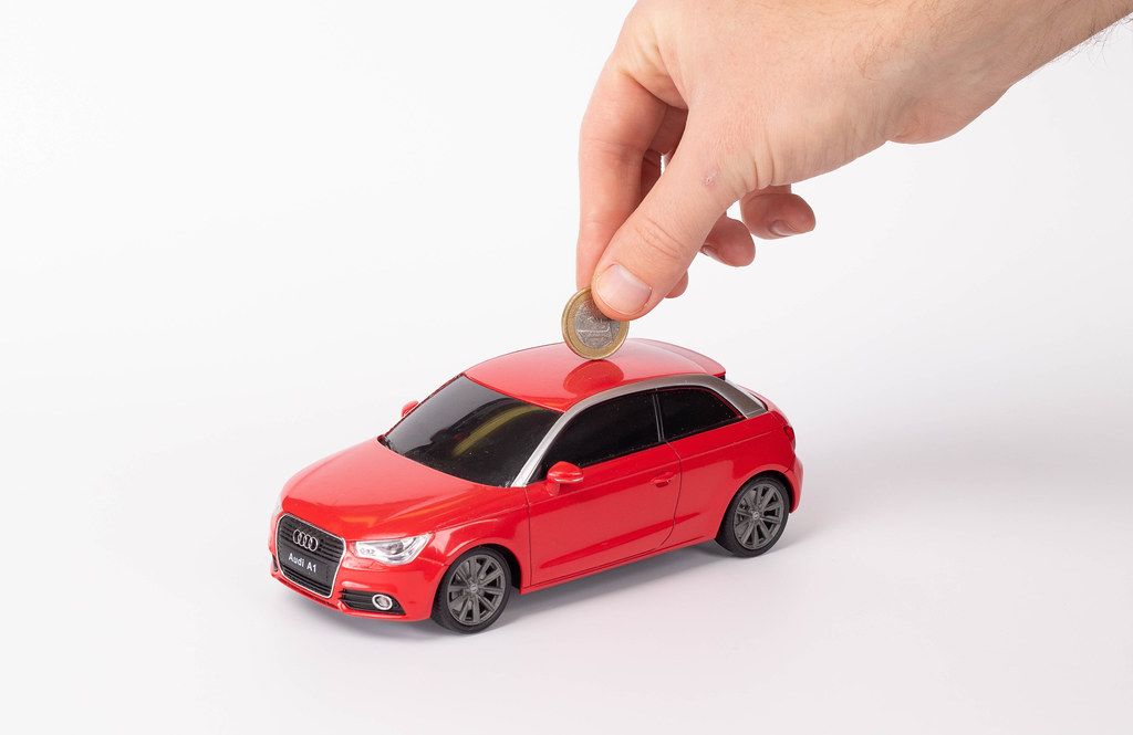 Putting coin into the car on white background