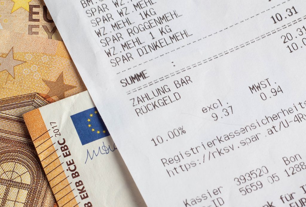 Quittung über Einkauf im Supermarkt liegt auf Euro-Banknoten