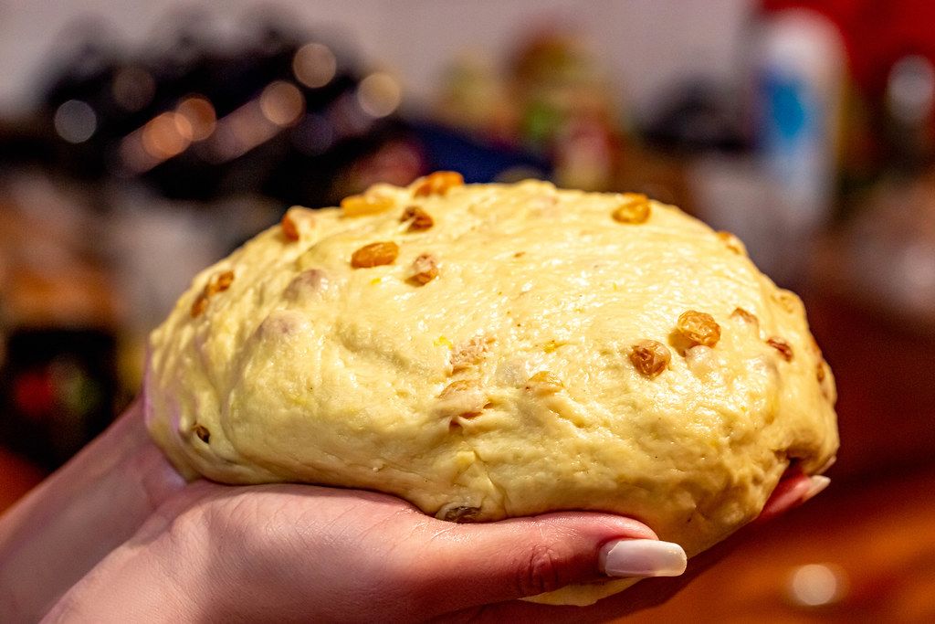 Raw dough with raisins for buns in women's hands