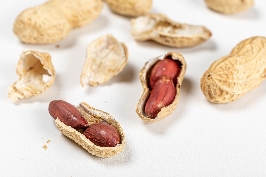 Raw peanuts in a whole shell and peanuts in a broken shell on a white background