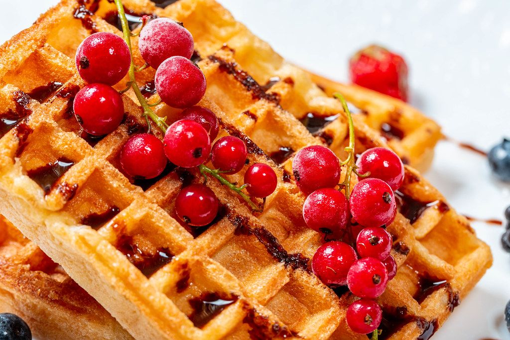 Red currant on waffles with chocolate topping close-up