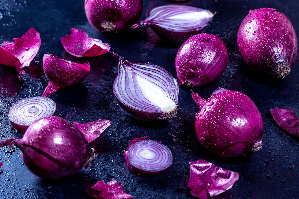 Red onion whole and halves on black background. Flat lay from above