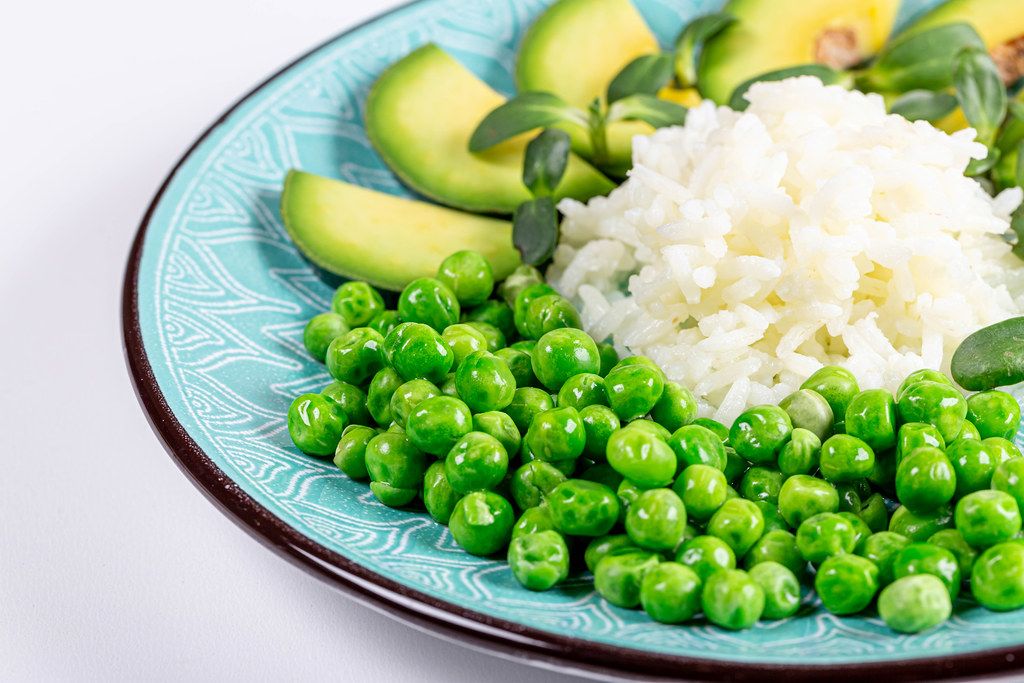 Rice with fresh avocado, green peas and sunflower microgreens