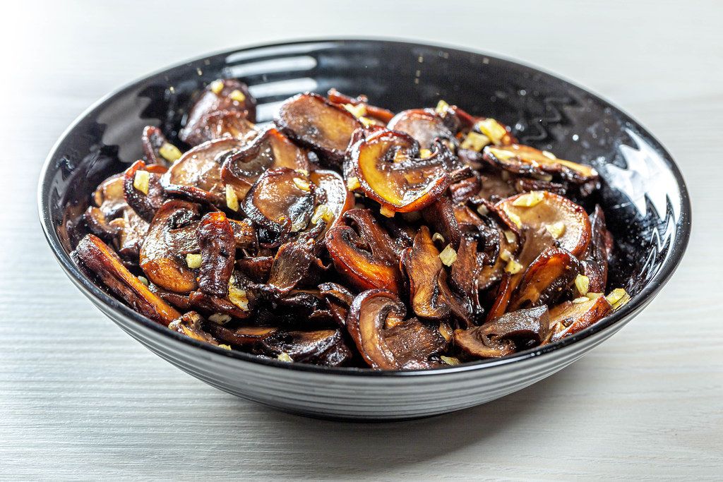 Roasted mushrooms with garlic on black bowl