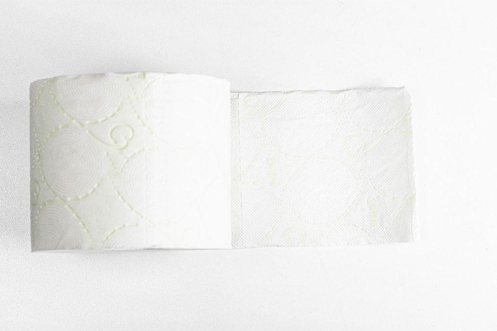 Roll of soft white toilet paper on a white background, top view