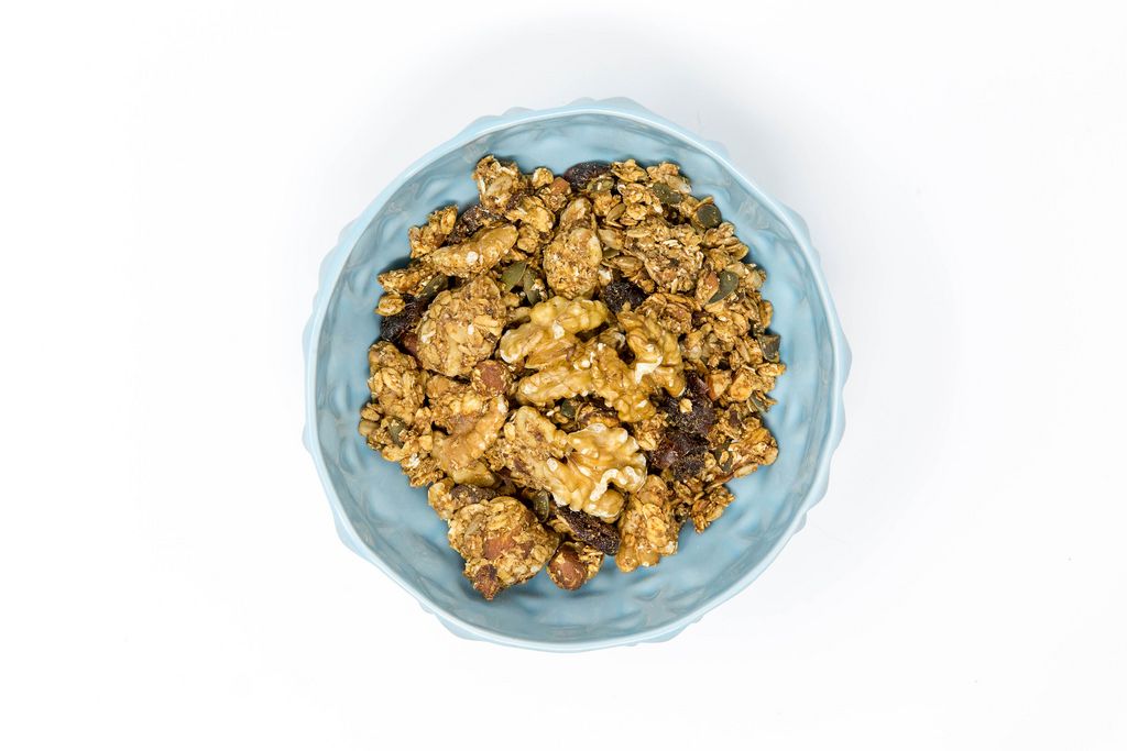Rollagranola - Vegan, gluten free, oat cluster snack with californian walnuts and pumpkin seeds in a light blue bowl - top view