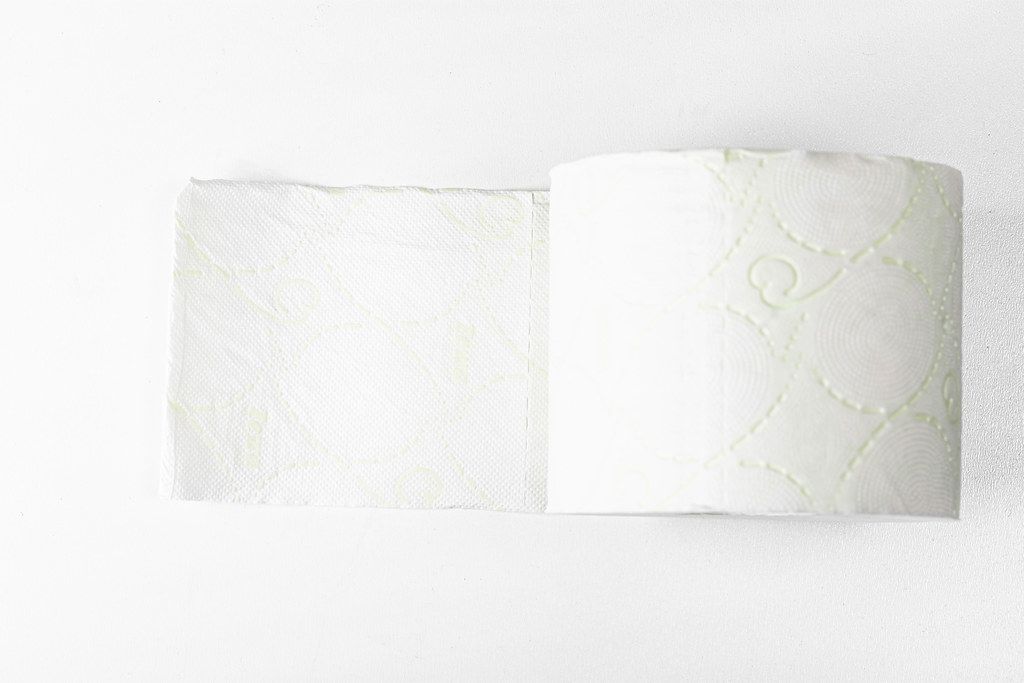 Rolle weiches, weißes Toilettenpapier auf weißem Hintergrund. Aufnahme von oben