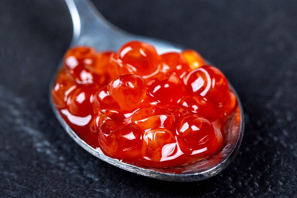 Roter Kaviar im silbernen Löffel auf schwarzem Hintergrund