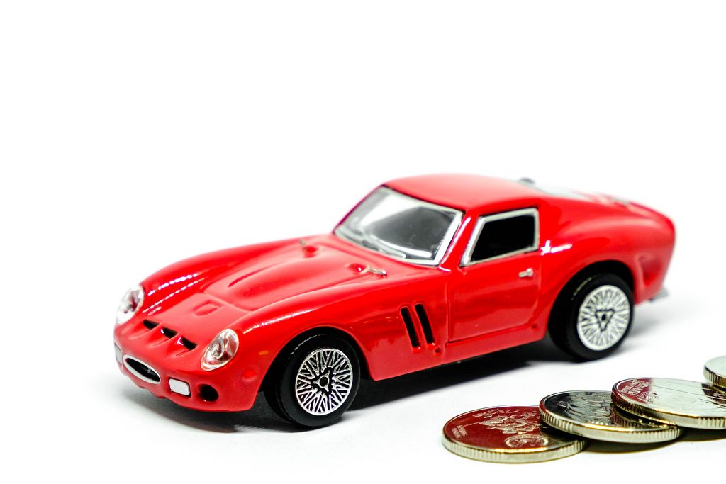 Rotes Spielzeugauto mit Münzen auf weißem Hintergrund