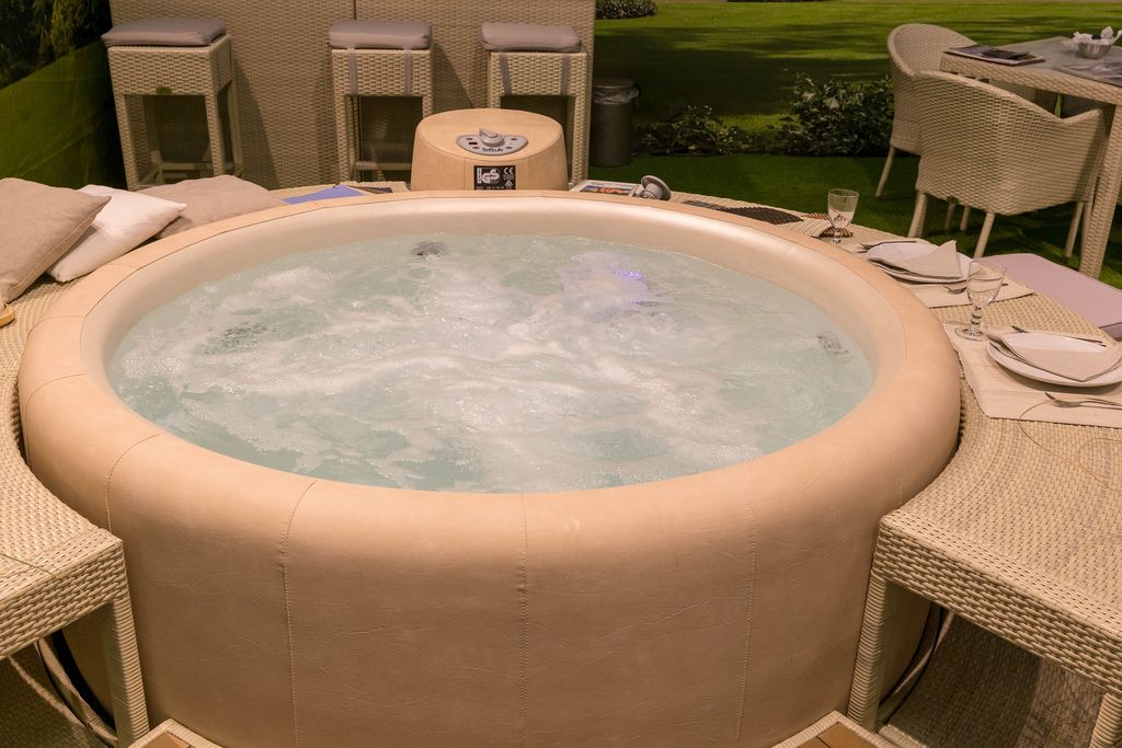 Round whirlpool with beige leather cover and matching side tables made of rattan