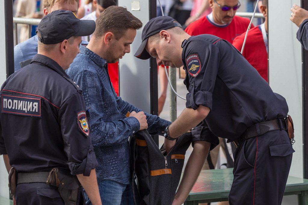 Russische Polizisten durchsuchen den Rucksack eines Mannes
