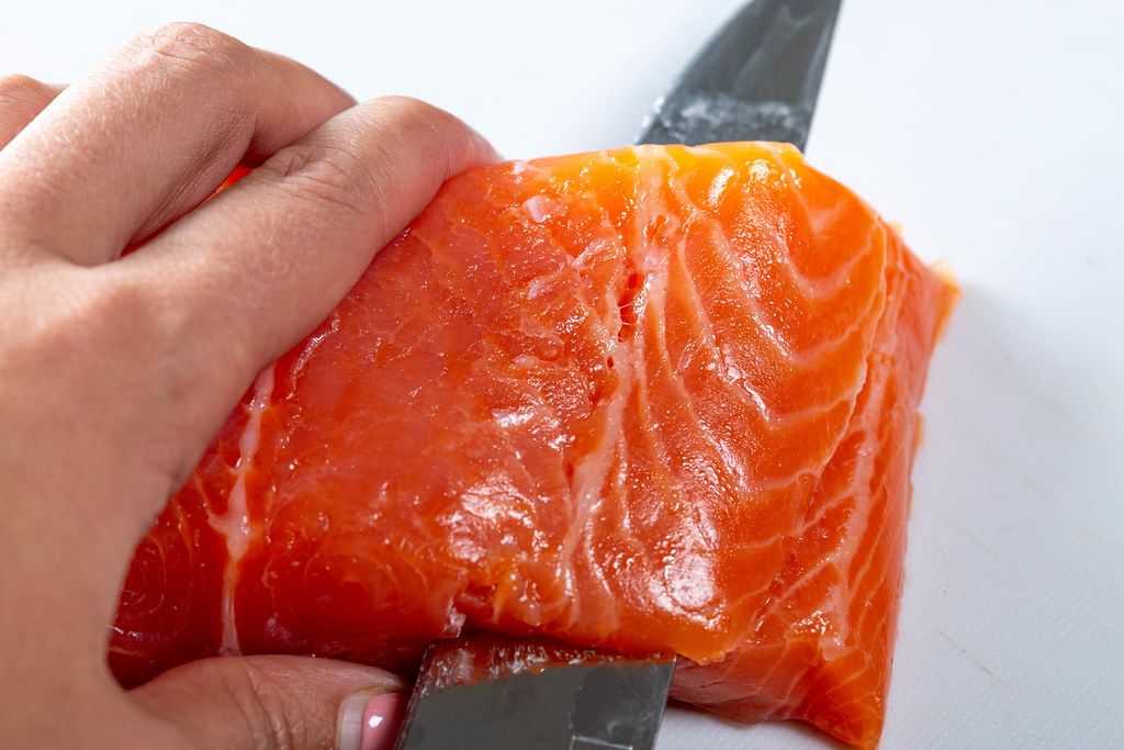 Salmon fillet is cut with a knife. Close up