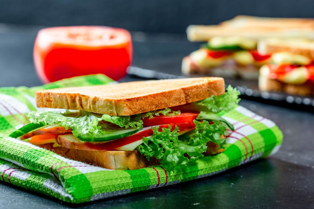 Sandwich with lettuce, tomatoes, cucumbers and cheese on a kitchen green towel