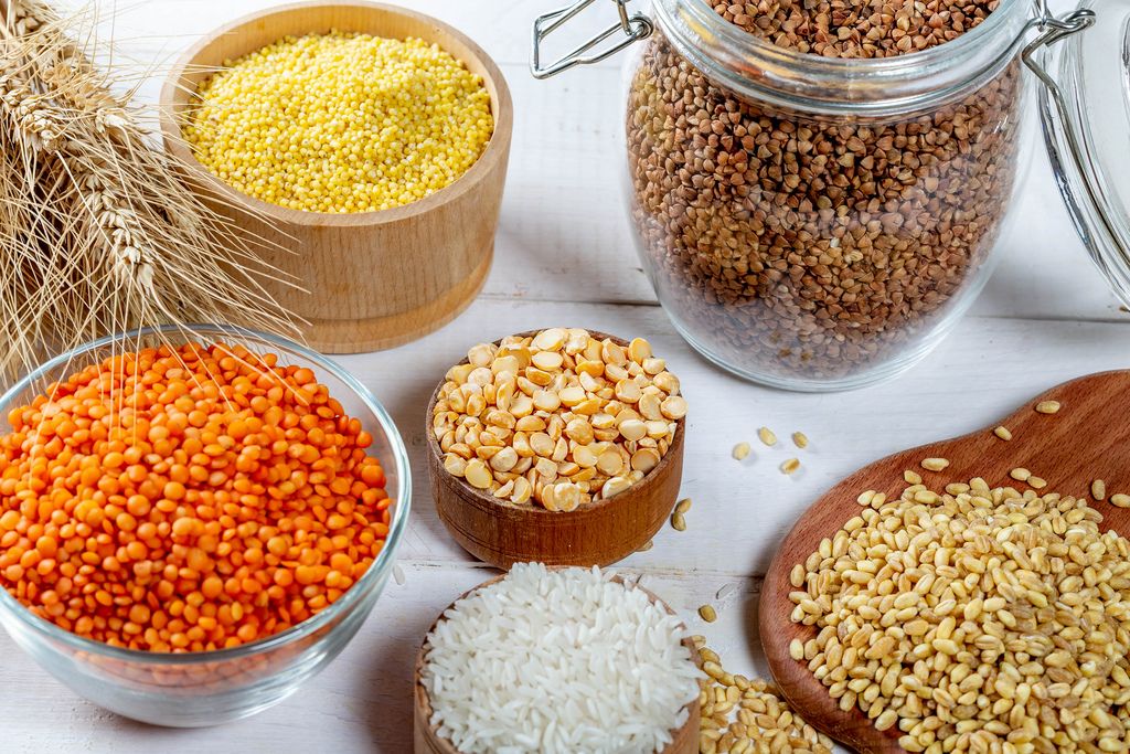 Schalen mit verschiedenen Getreidesorten wie Reis, Hirse, Linsen, Erbsen und Buchweizen