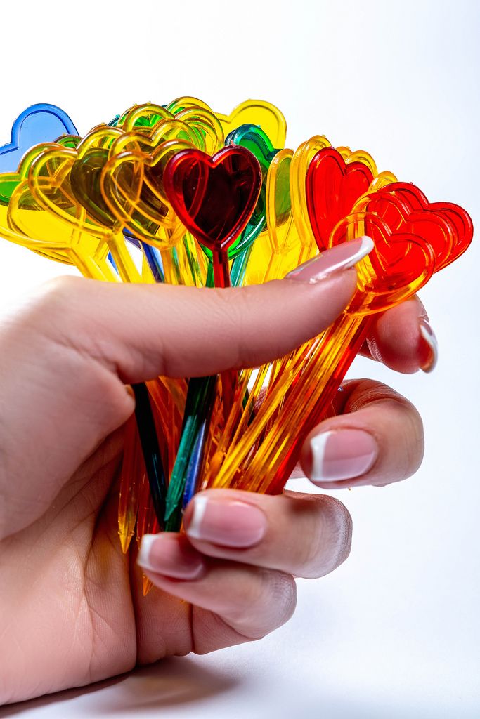 Scharfe mehrfarbige Plastikspieße mit Spitzenherzen in der Hand einer Frau