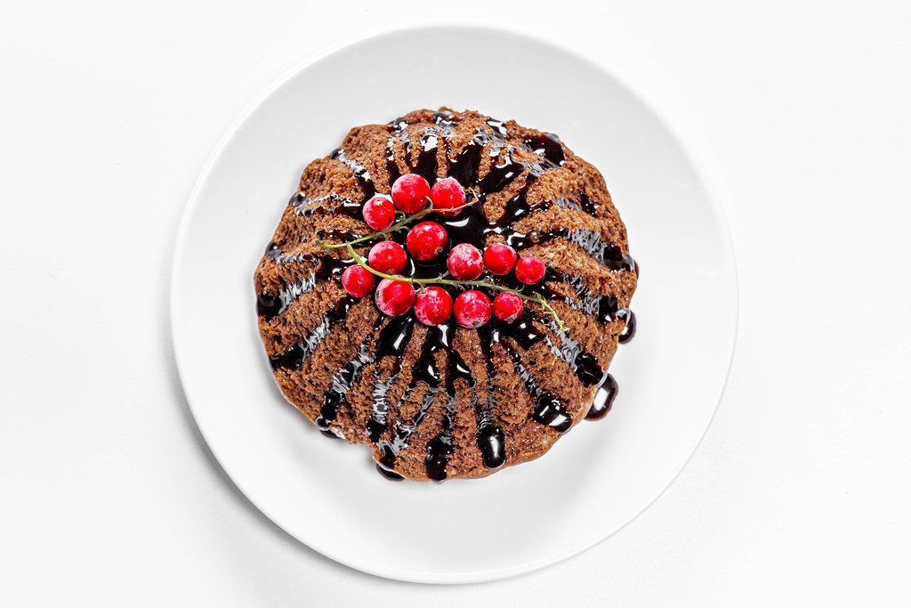 Schoko-Cupcake mit roten Waldfrüchten und Schoko-Topping: Aufnahme von oben auf weißem Hintergrund