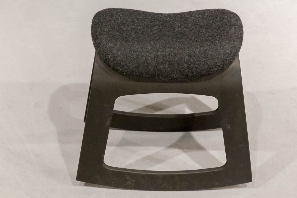 Schwarzer Hocker aus Kunststoff mit Sitzfläche bezogen mit Filz vor weißem Hintergrund