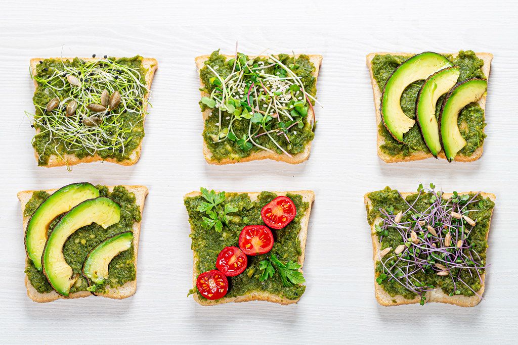 Set of different sandwich with herbs, micro greens, vegetables and seeds on white wooden background. Top view (Flip 2019)