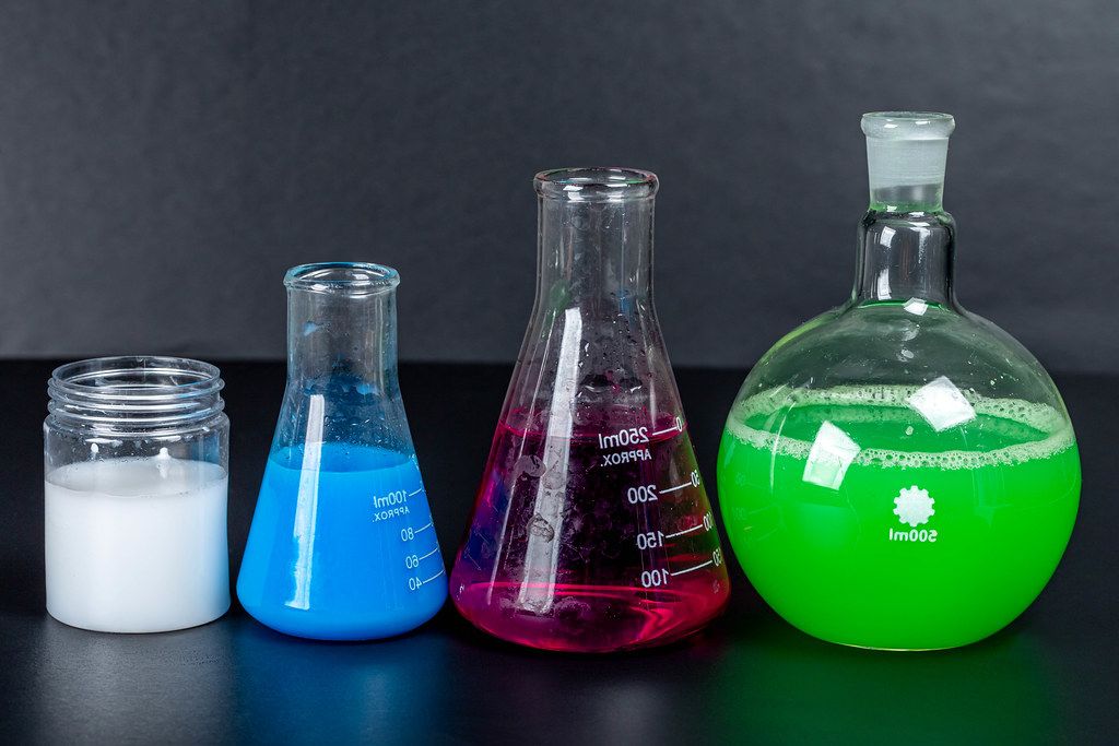 Set of laboratory glassware with chemical multi-colored solutions on a black background (Flip 2020)