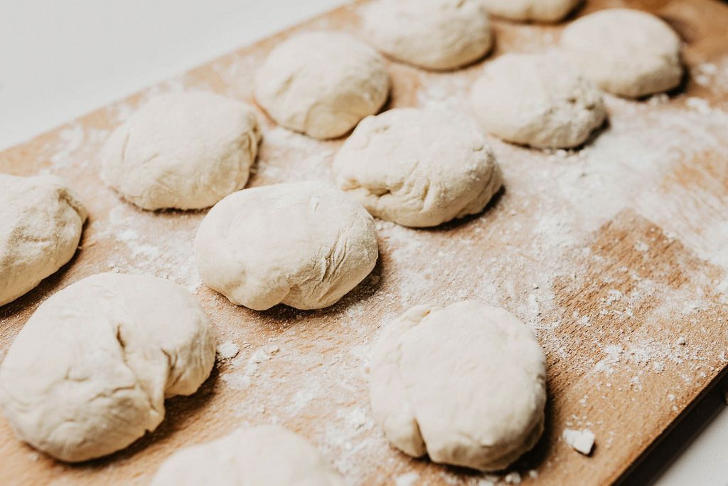 Set of raw dough rolls on wooden board.