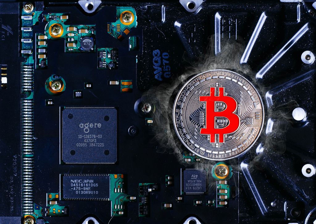 Silver Bitcoin on a background of computer mining electronic parts